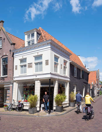 couple on bicycle passes corner shop in old street of edam in hollandのeditorial素材