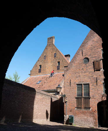 man in red shirt repairs medieval building in old centre of zutphen in the netherlandsのeditorial素材