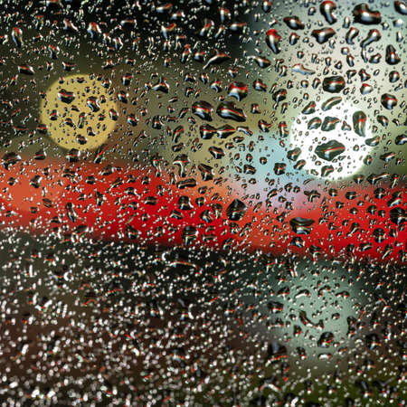 colorful diffuse unsharp lights behind glass window with rain dropsの写真素材