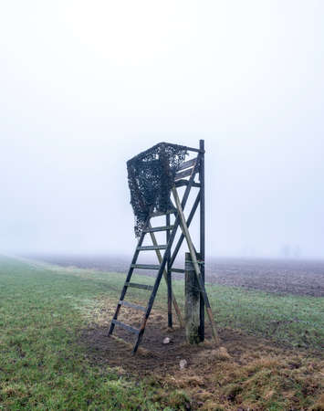 high seat for hunting in green winter field near utrecht in the netherlands on misty winter dayの写真素材