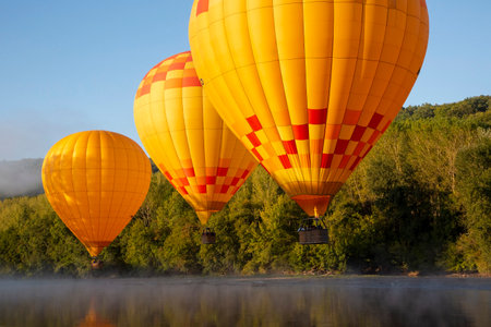 hot air balloons fly low over dordogne river in southern franceの写真素材