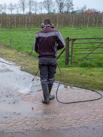 wadenoijen, netherlands, April 10, 2023: man cleans driveway with pressure washer near farm in the netherlandsの写真素材