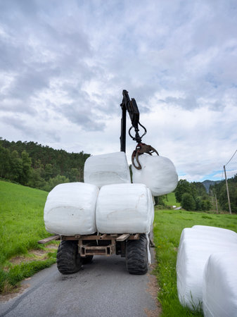 loading white grass rolls on country road in norwayの写真素材