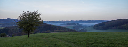 sunrise over early morning landscape with fog in German Sauerlandの写真素材
