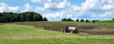 French farmer in tractor spreads manure on field in the area of Champagne Ardennes in Franceの写真素材