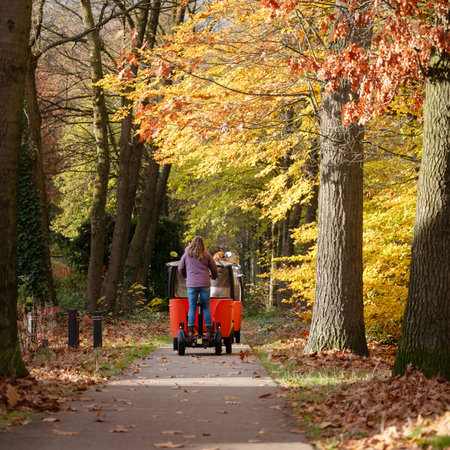 young children transported in electrical vehicle called stint on bicycle road in the autumn near Utrecht in the Netherlandsの写真素材