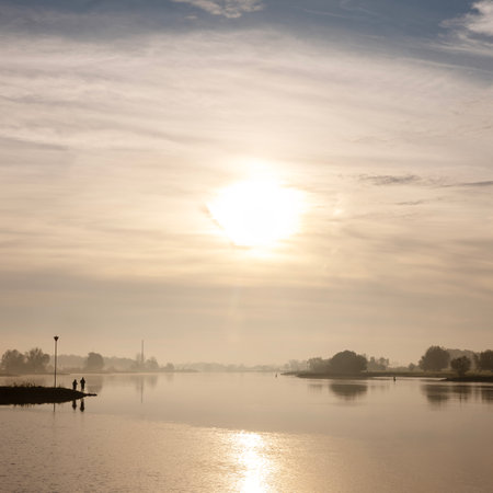 silhouettes of men fishing in river lek at sunrise on early morning in the fallの写真素材