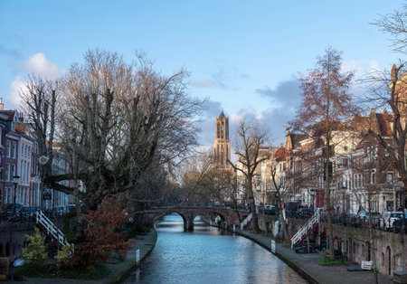 high dom tower and blue sky reflected in water of canal in dutch city of utrecht in winterの写真素材