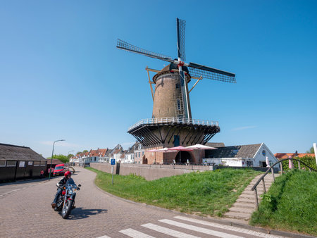 wijk bij duurstede, netherlands, april 20, 2025: motorcycle passes windmill at old fortified town of wijk bij duurstede in the netherlands on sunny day in springの写真素材