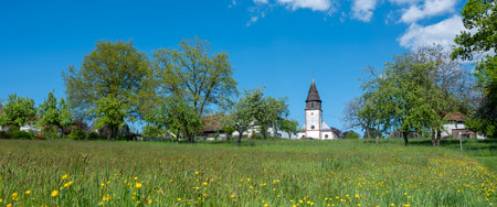 blue sky anbd spring flowers near village church in nature park saar hunsrueck near trier in germanyの写真素材