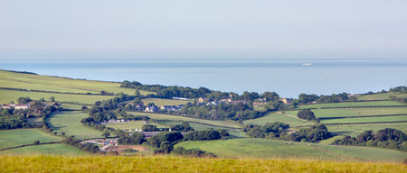 meadows and village in south devon with ship on blue sea in the background