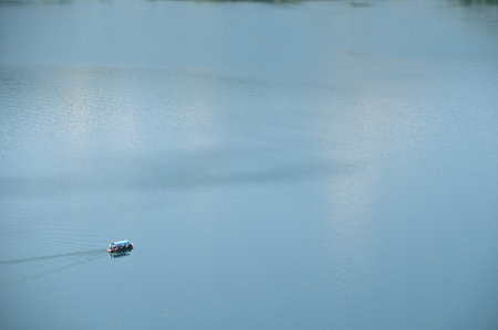 A small boat crossing the calm lakeの写真素材