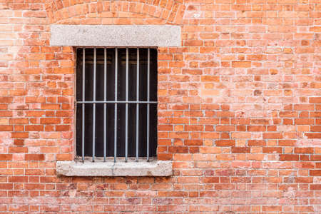 Red brick wall with metal frame window, nobody