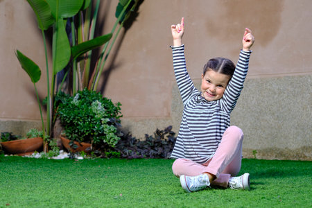 Happy girl sitting on the grass with open arms.の写真素材