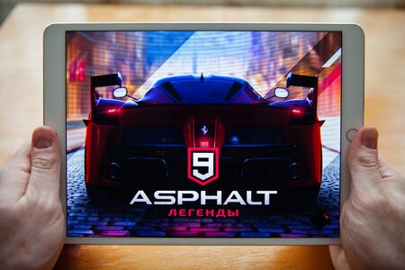 Moscow / Russia - February 25, 2019: White ipad in hand. On the screen loading the game asphalt