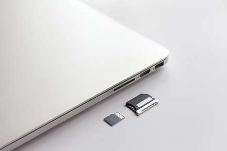 Closed metal laptop on a white table. Near the adapter to the card reader