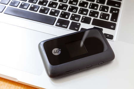 Moscow / Russia - May 11, 2019: Black 4G mobile Wi-Fi router lying on the keyboard macbookのeditorial素材
