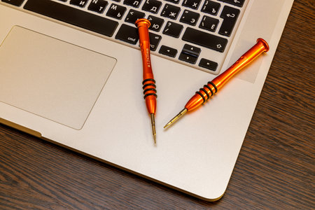 two small screwdrivers lie on a laptopのeditorial素材