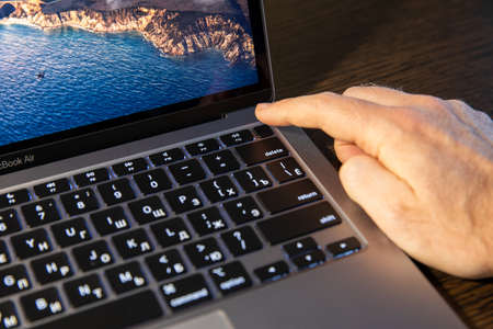 Moscow / Russia - 8 March 2021: Macbook with Touch ID is unlocked with a fingerのeditorial素材