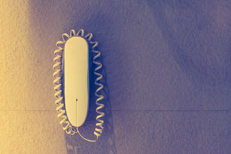 intercom home hung on a white wall,White plastic phone on a wall for emergency call or support tone vintageの写真素材