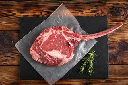 tomahawk ribeye steak on black stone plateの写真素材