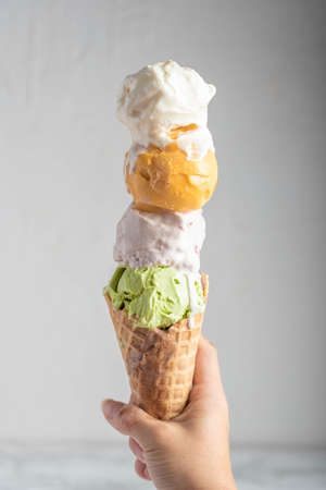 hand holding four scoops of ice cream in waffle coneの写真素材