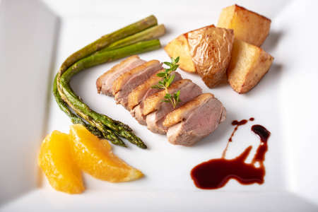 sliced roasted duck with red wine sauce and orange