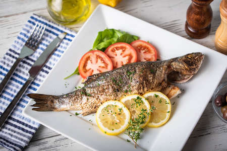 greek style grilled sea bass on rustic backgroundの写真素材