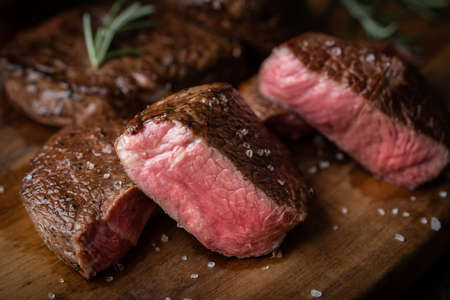 rare grilled tenderloin beef steak on cutting board with vegetables
