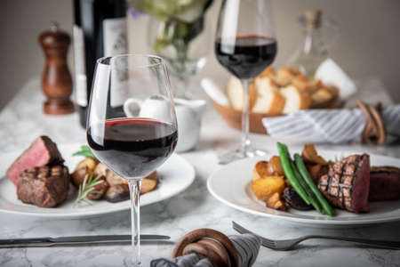 wine glasses on dining table with steakの写真素材