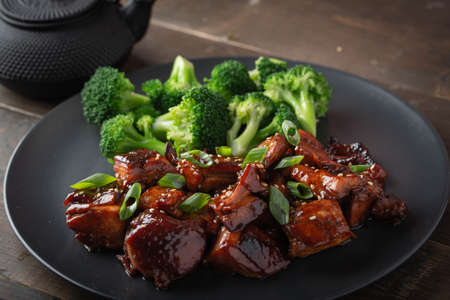 teriyaki chicken and broccoli on black plate