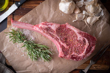 seasoned tomahawk steak meat on wooden board