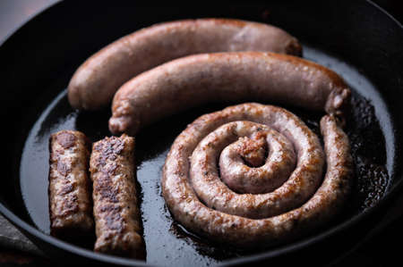 cooking sausages on iron skillet panの写真素材