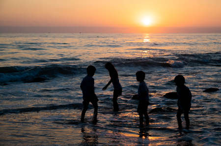 kids playing on beach at sunset timeの写真素材