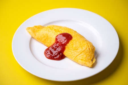 plain omelette with tomato ketchup on yellow backgroundの写真素材