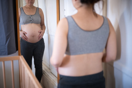 pregnant asian women checking her body with mirror
