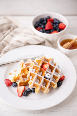 half eaten belgium waffle with strawberry, blueberry and honeyの写真素材
