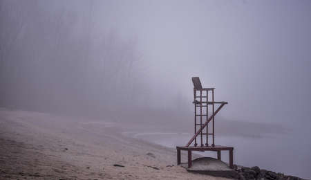 Empty lifeguard chair on the beach - A lifeguard seat stands empty in fog on a November beach in Ontario Canada.の写真素材