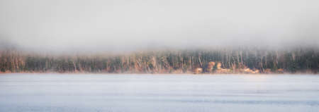 Fog rising from Ottawa River - horizontal divide of two environments - air and water creates a visual spectacle.  Blanket of fog lifting off the Ottawa Riverの写真素材