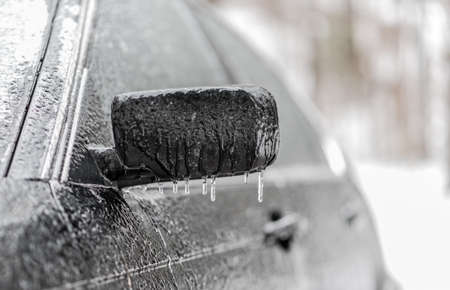 Freezing rain ice coated car.  Black vehicle car covered in freezing rain, Icicles hanging from side mirror.  bad driving weather in freezing rain.  Lousy weather.の写真素材