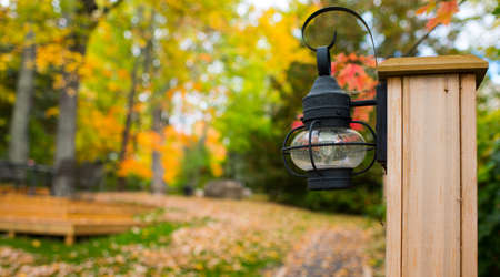 Walking path in October autumn colors.  A lantern stands ready on a post to light the way.の写真素材