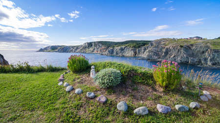 Garden by the sea in Twillingate, Newfoundland.   Simple flower and shrub garden in summer at the top of a cliff near the ocean's edge in a Newfoundland village.の写真素材