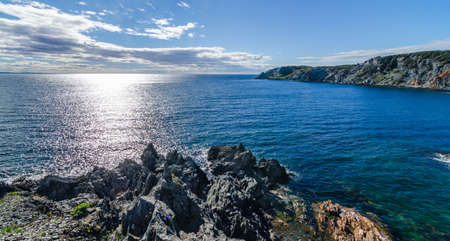 Sun shines bright on the Atlantic Ocean.  View of the cove and the Atlantic from a high cliff in Crow Head, Newfoundland, Canada.の写真素材