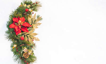 Christmas holiday faux poinsettia pine wreath adorned with gold leaf ribbon, Christmas balls and holly, resting on natural snow with white copy space.の写真素材