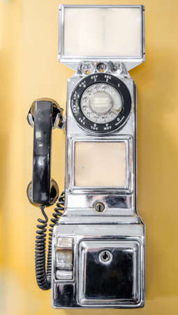 Vintage, out of service, retro, chrome plated, old style, coin operated, public, pay telephone from an earlier time in technology.の写真素材