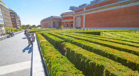 Madrid, Spain, November 9th, 2013,  Tourism in Spain.  Man takes a smoke break beside the labyrinth of diagonal rows of shrubbery behind Prado Museum in Madrid Spain.のeditorial素材