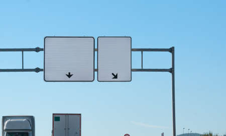 Two blank highway signs, each has arrow pointing direction where to go,  insert your text, tops of...