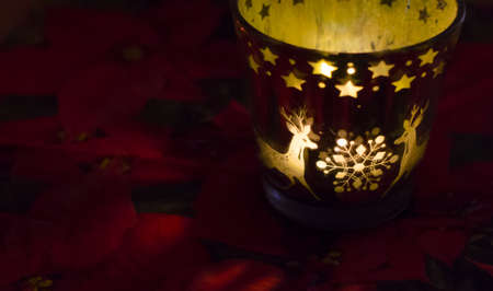 Christmas candle holder alight with a holdiay red glow, depicts scenes of winter and snow by the flame within.の写真素材