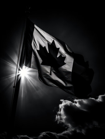 Black and white image of a Canadian flag waving in the wind with the sun shining through the cloudsの素材