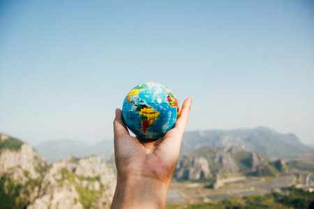 Holding a globe on the background of mountains and blue sky.の写真素材